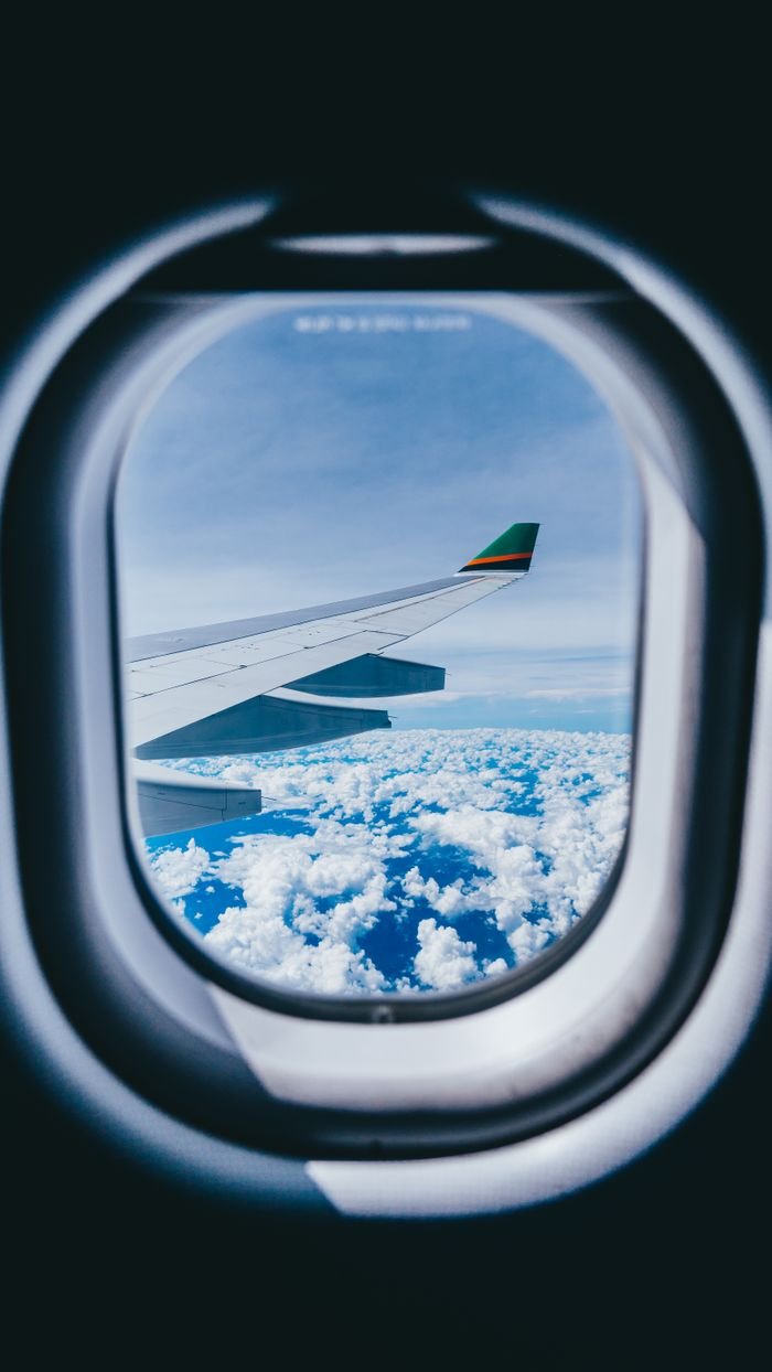 Services Scenic view of aircraft wing and sky seen through a plane window, captured in flight.